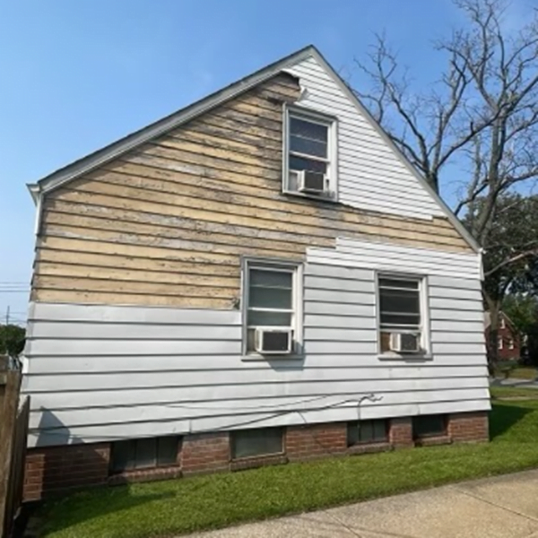 A house with siding that has been blown off by the wind.